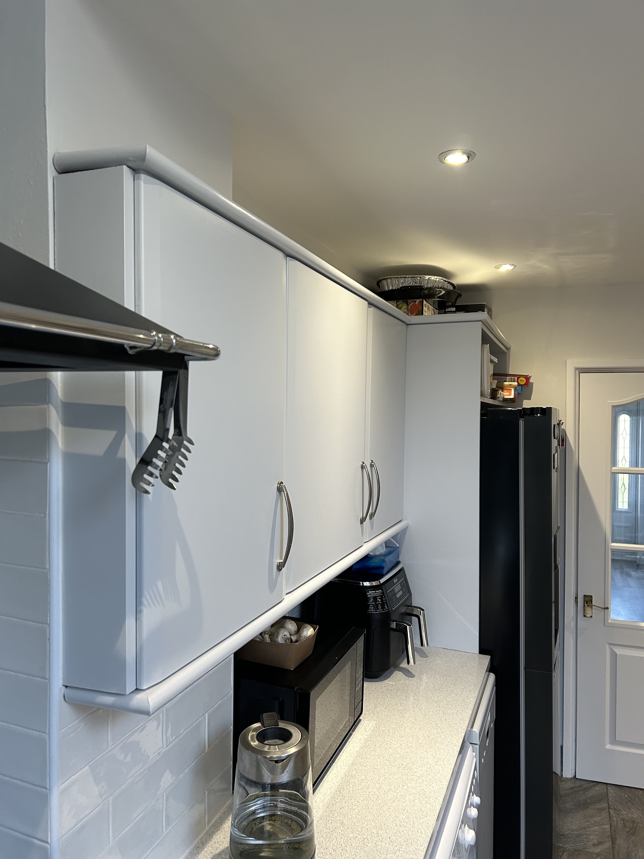 Galley kitchen with white painted wall units and fresh white walls